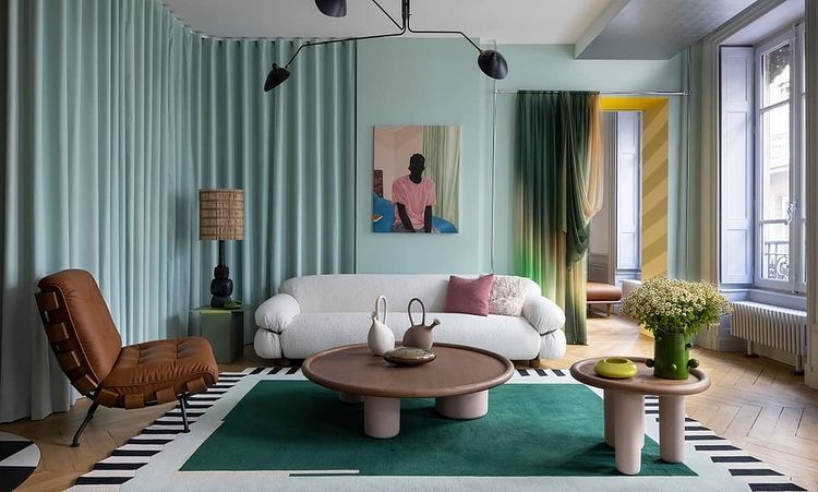 Interior of blue living room with modern influence and curved furniture like a matching round coffee and end table along with a leather accent chair and a white couch