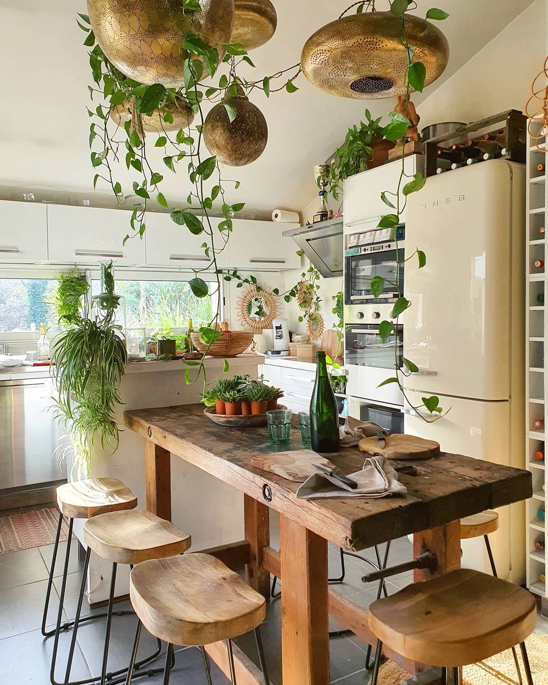 Amidst plants, an upcycled wooden table has barstools with smooth, wooden seats. Photo by Instagram user @zebodeko. 