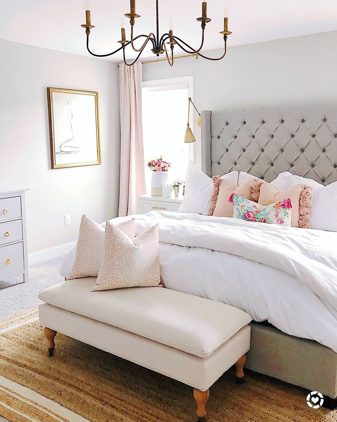 Off white upholstered bench at the foot of a tufted bed. Photo by Instagram user @theviewfromtobaccoroad