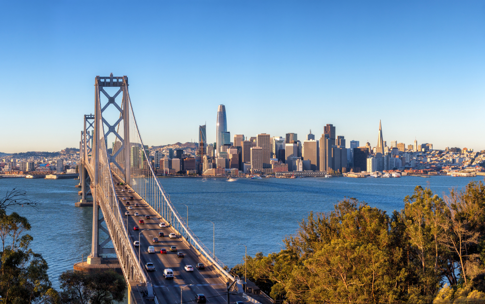 Photo of Bay Bridge with skyline of San Francisco in the background.