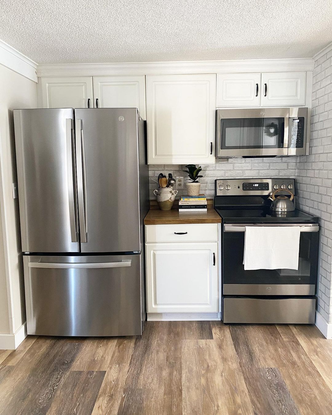 Small kitchen with stainless steel fridge, oven, and microwave. Photo by Instagram user @hearthandclove