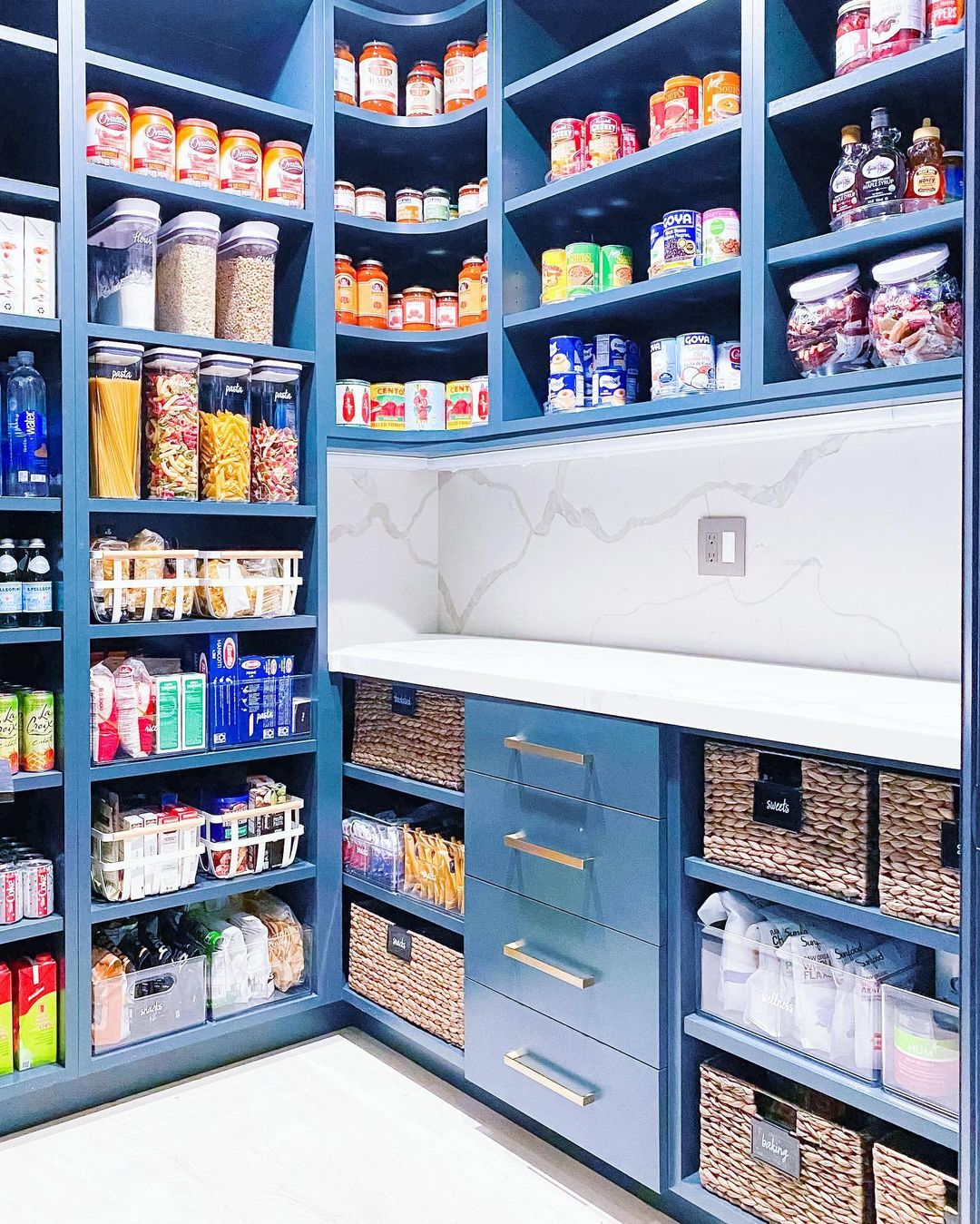 Neatly organized blue pantry with blue shelving, drawers, and counterspace. Photo by Instagram user @thehomeedit