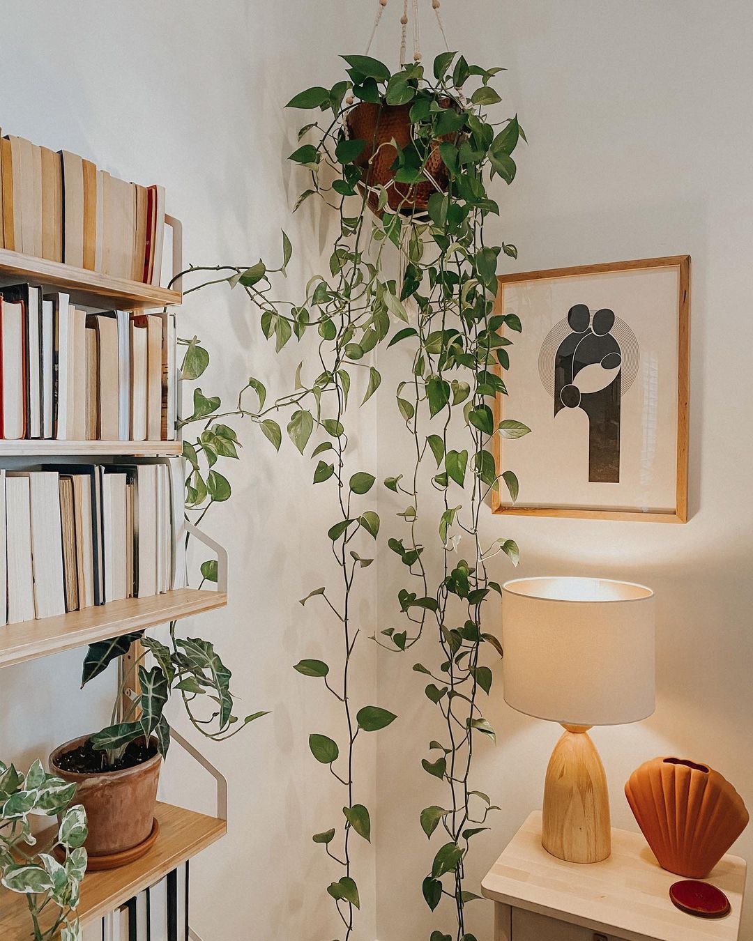Corner of Japandi style room with a framed print and hanging pothos plant. Photo by Instagram user @coffeeandpoemss