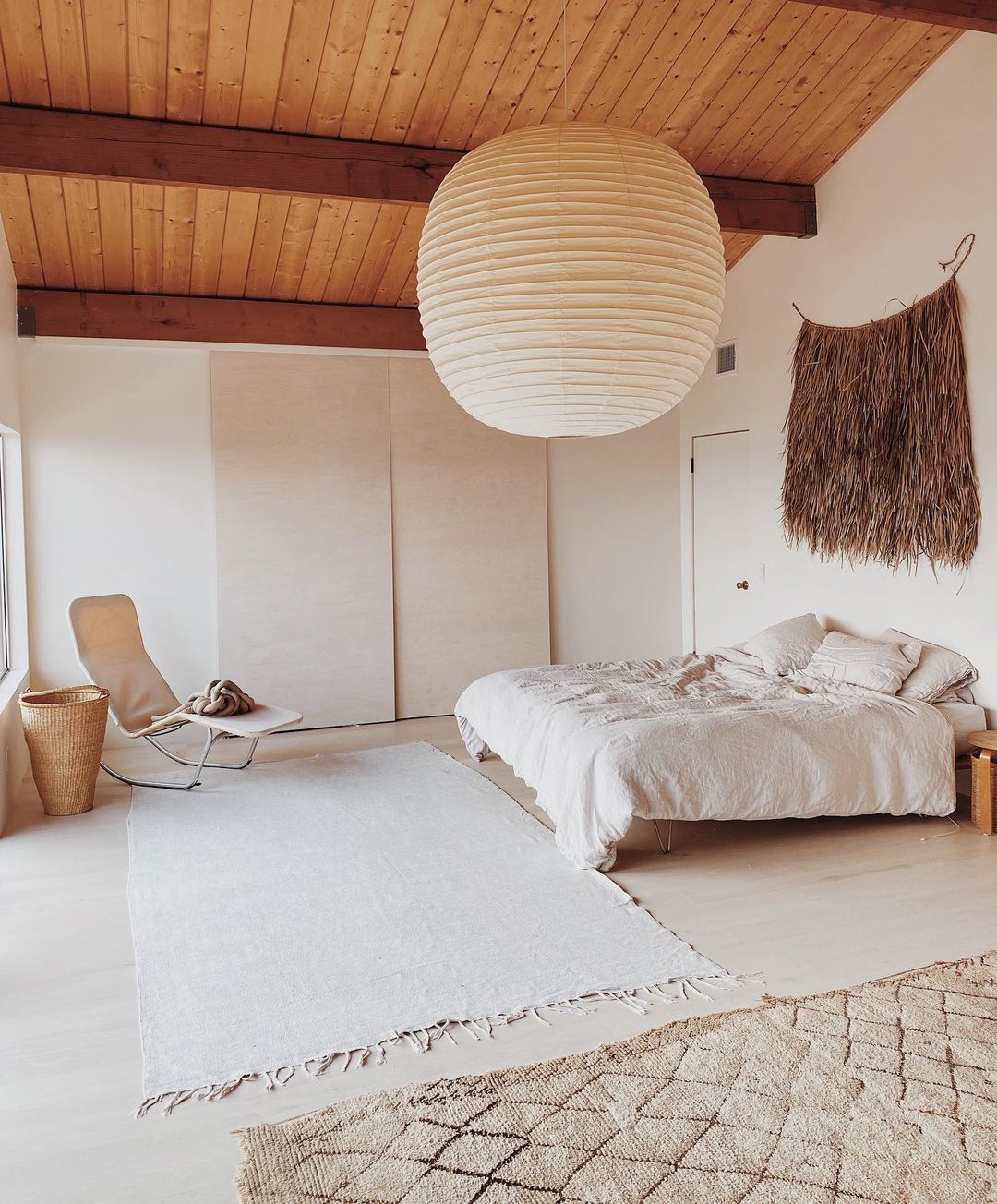 Airy, minimally designed bedroom with large paper lantern style light fixture. Photo by Instagram user @maraserene