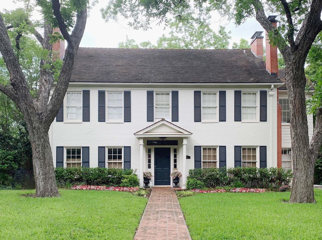 White brick colonial home with blue shutters in Alamo Heights, San Antonio. Photo by Instagram user @papermoonpainting