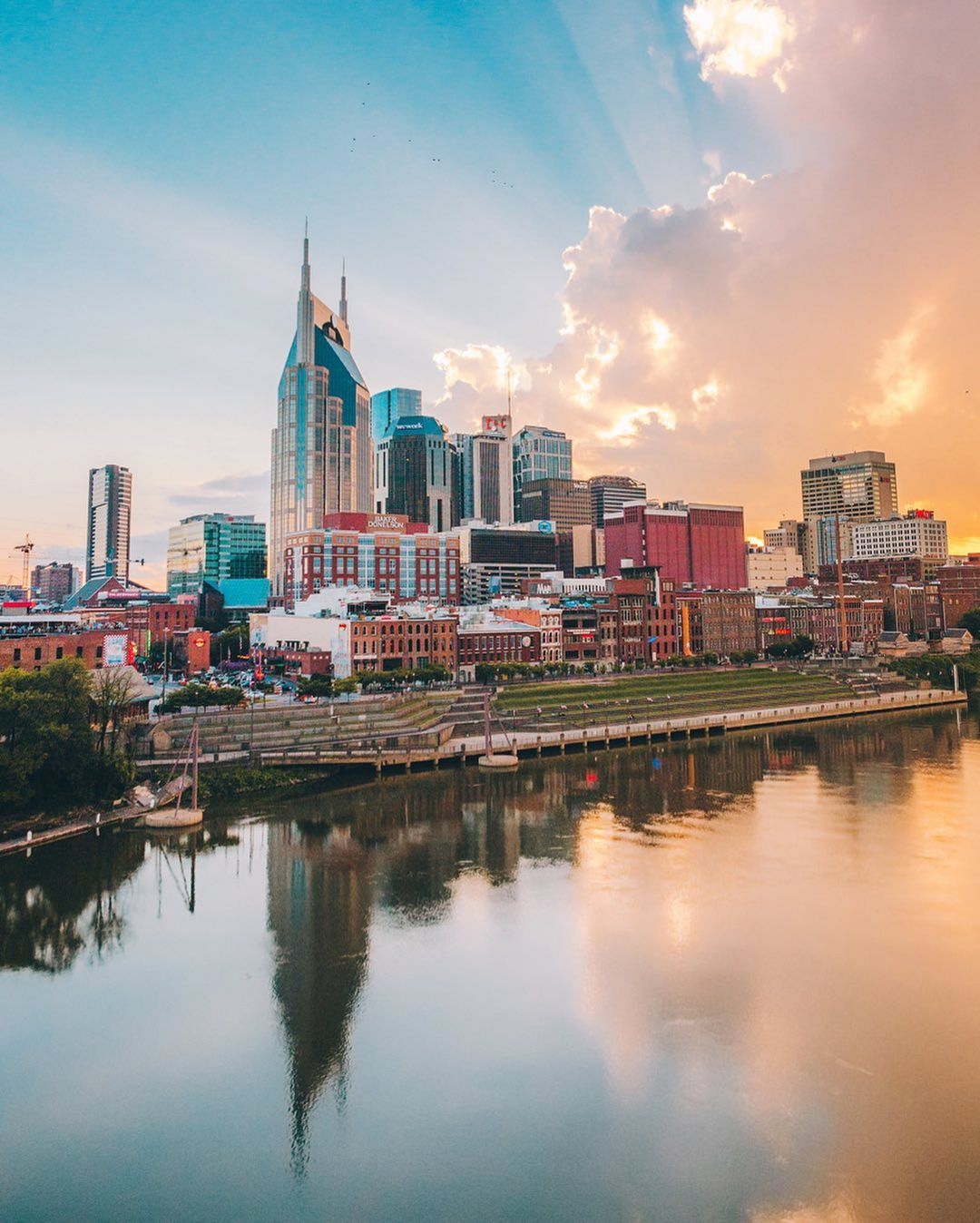 Skyline photo of Nashville with sun peeking through the clouds. Photo by Instagram User @jakesvisuals