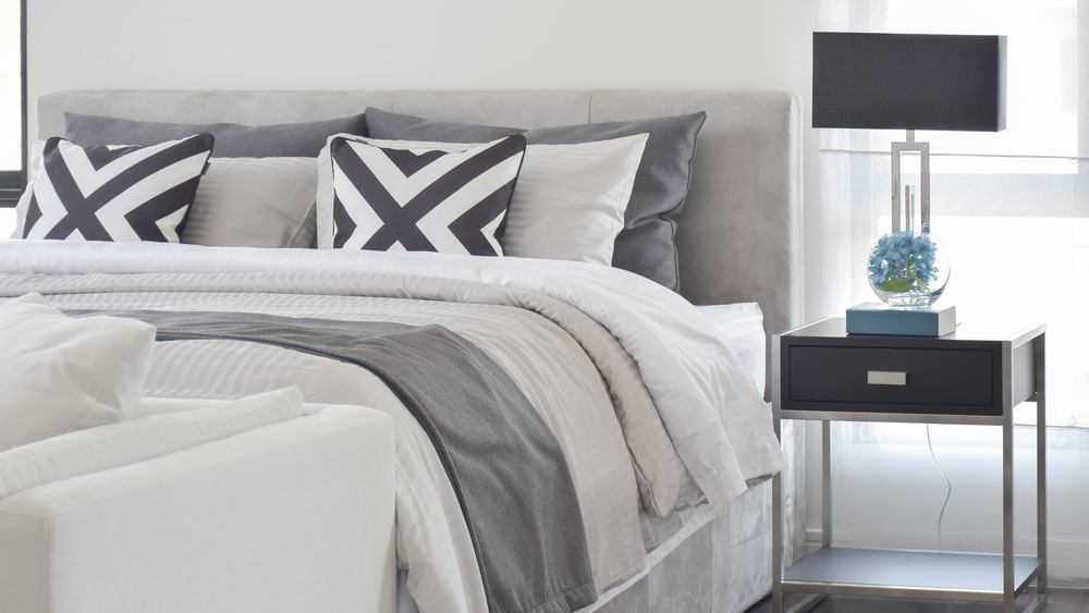 Gray and cream colored bedding with patterned pillows.