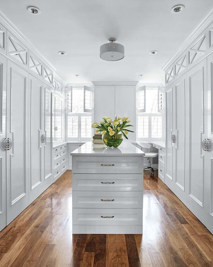 Spacious closet with white cabinets and island. Photo by Instagram User @stellabrendainteriors
