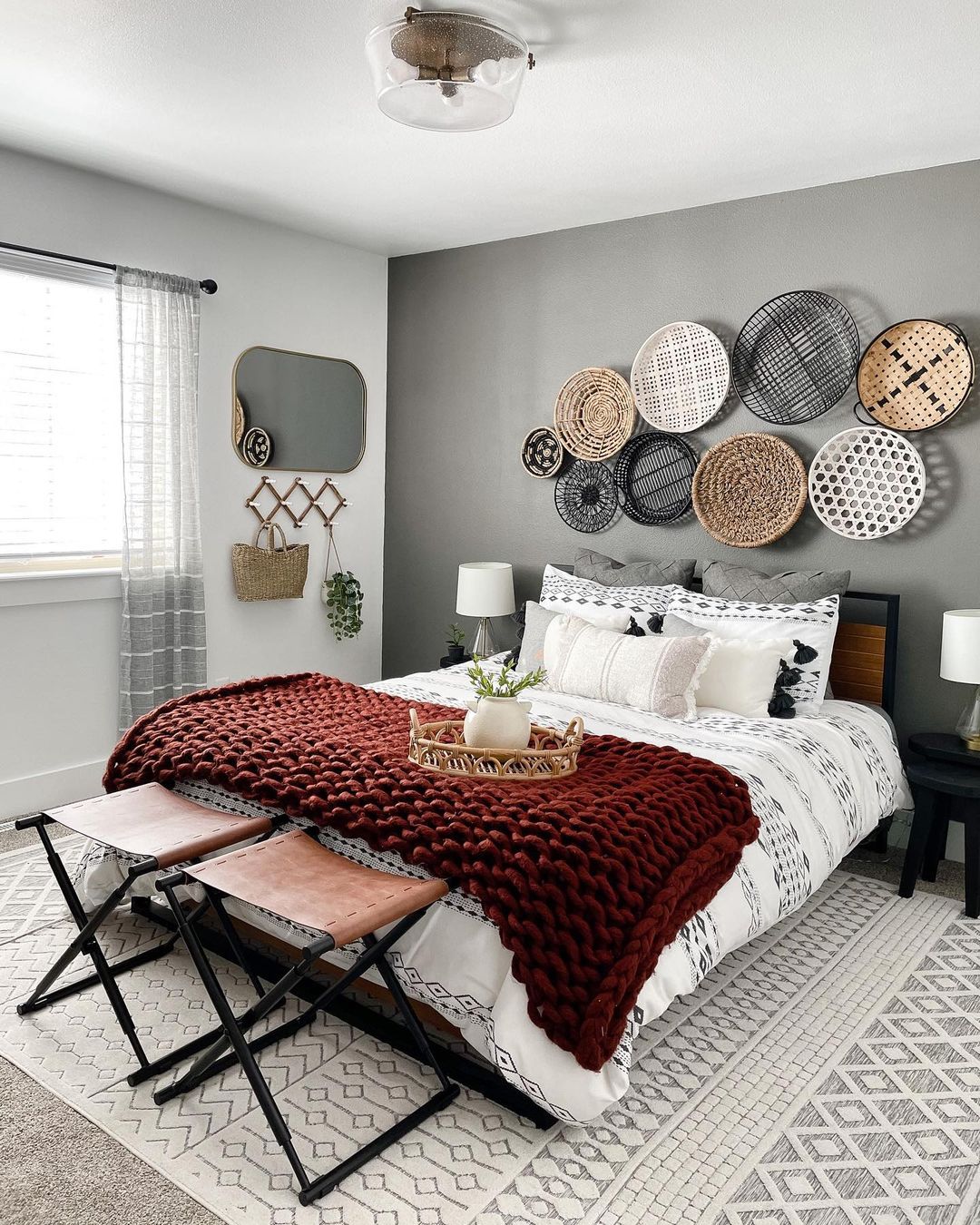 Cozy bedroom with gray accent wall and boho baskets hung on wall. Photo by Instagram User @meaganmarquisliving