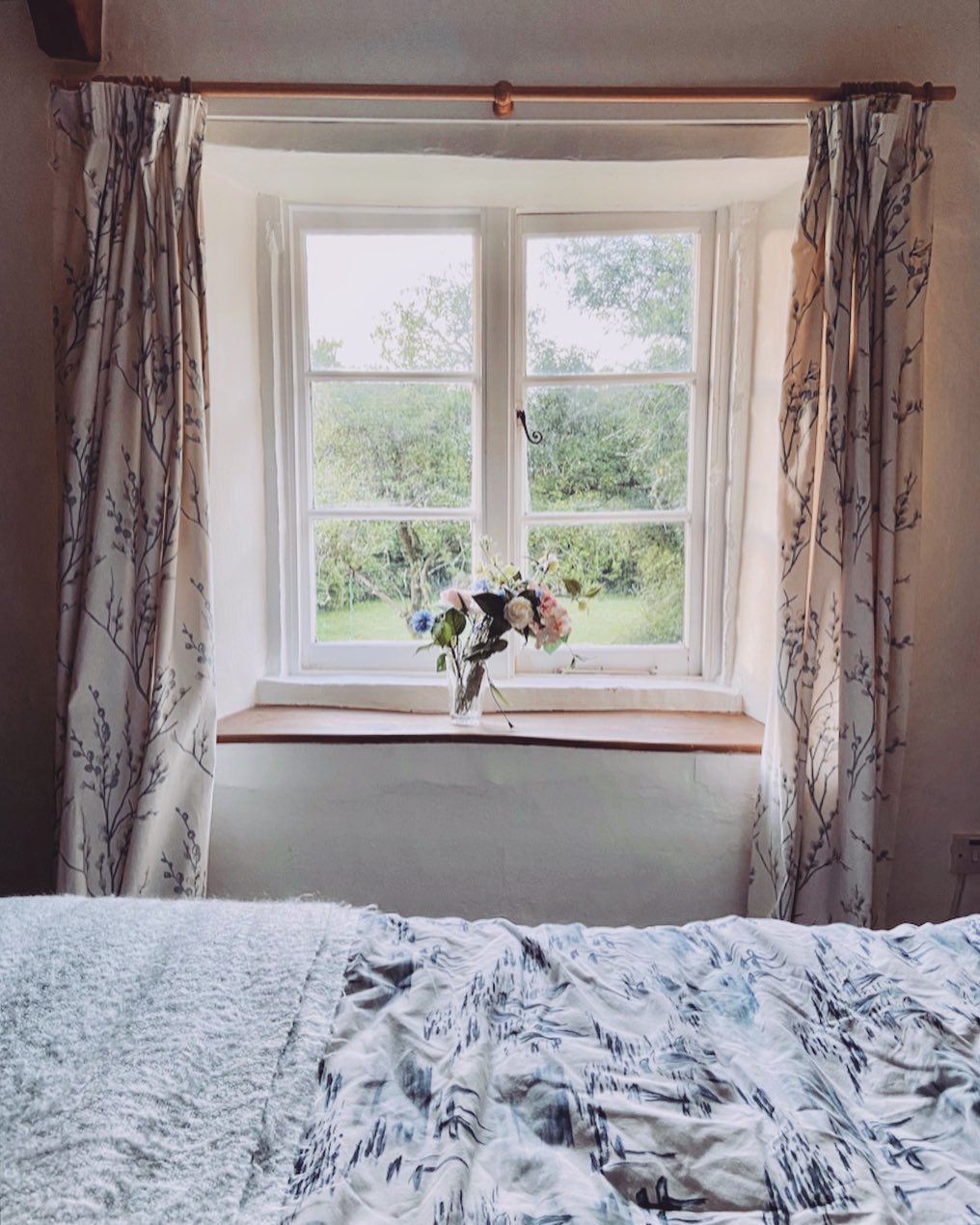 Cozy cottage bedroom with clean windows and flowers on windowsill. Photo by Instagram User @thesundayfeeling