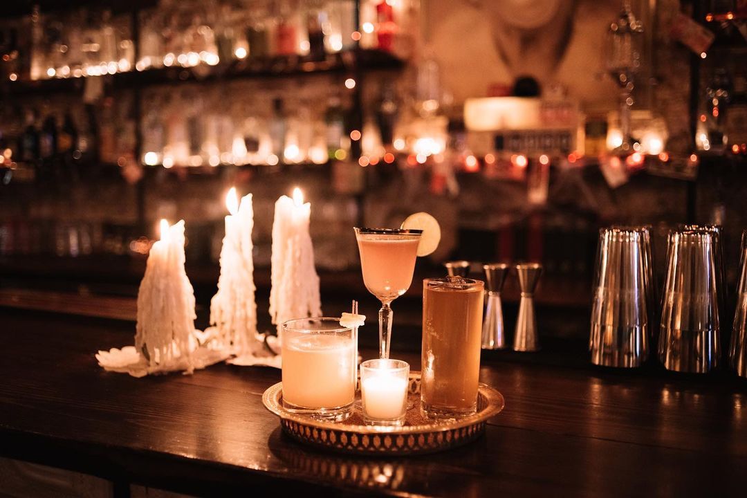 Tray with Fancy Drinks Next to Lit Candles. Photo by Instagram user @unknowncallerbar