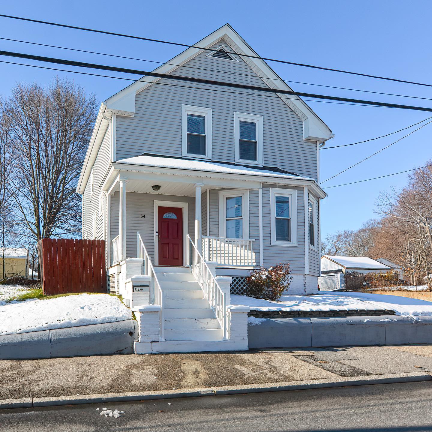 Two-story Colonial home with red door and white steps located in the Reservoir neighborhood in Providence, RI. Photo by Instagram user @rosannysellshomes. 