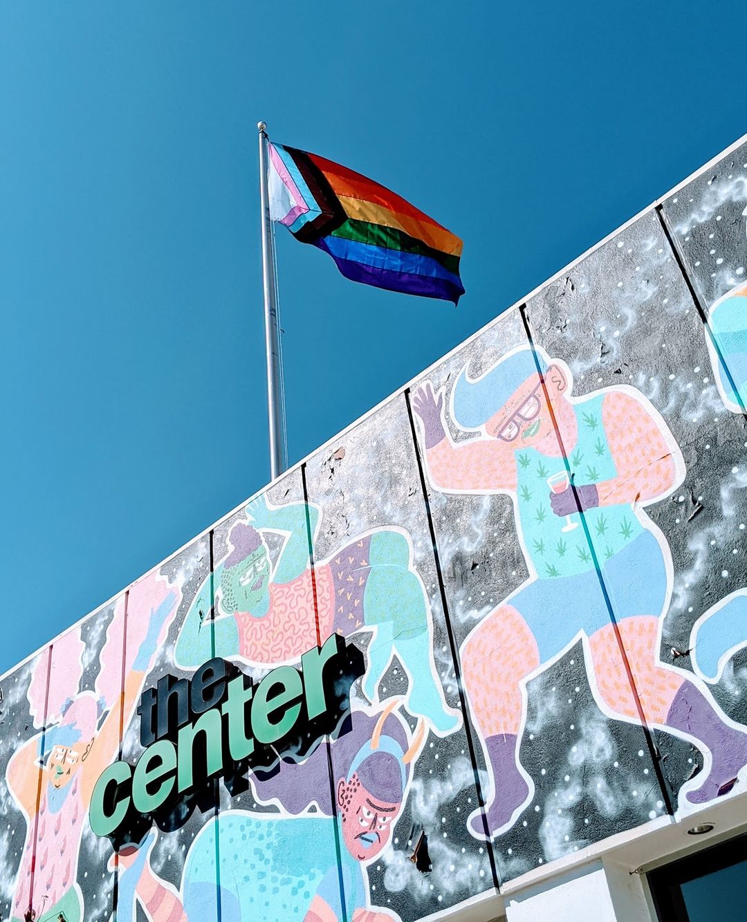 Sign of The Center featured amidst a mural that shows body positivity and gender inclusion, with a traditional rainbow Pride pattern, paired with Trans colors and black and brown stripes to "represent marginalised LGBT communities of colour." Photo by Instagram user @centerlb.