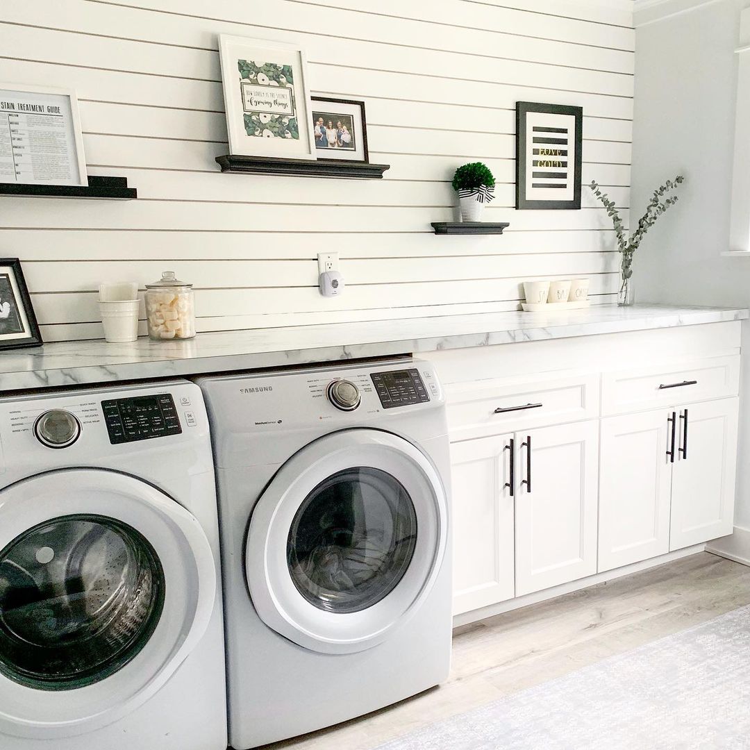 Large laundry room with white cabinets and shiplap walls. Photo by Instagram User @houseofnavy