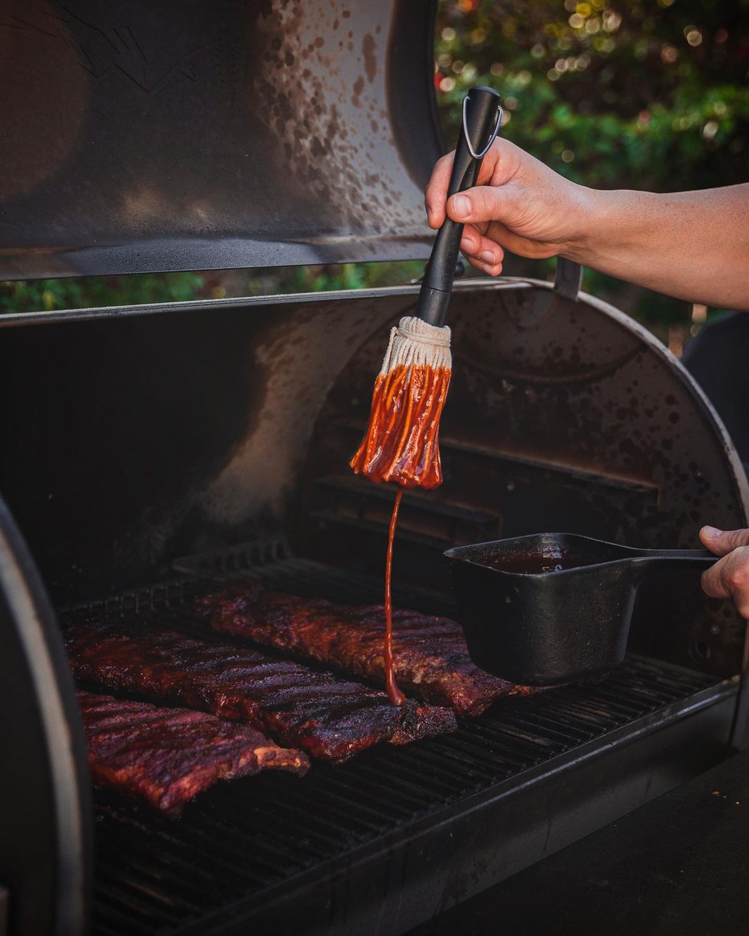 Person Brushing BBQ Sauce on Ribs. Photo by Instagram user @briewilly