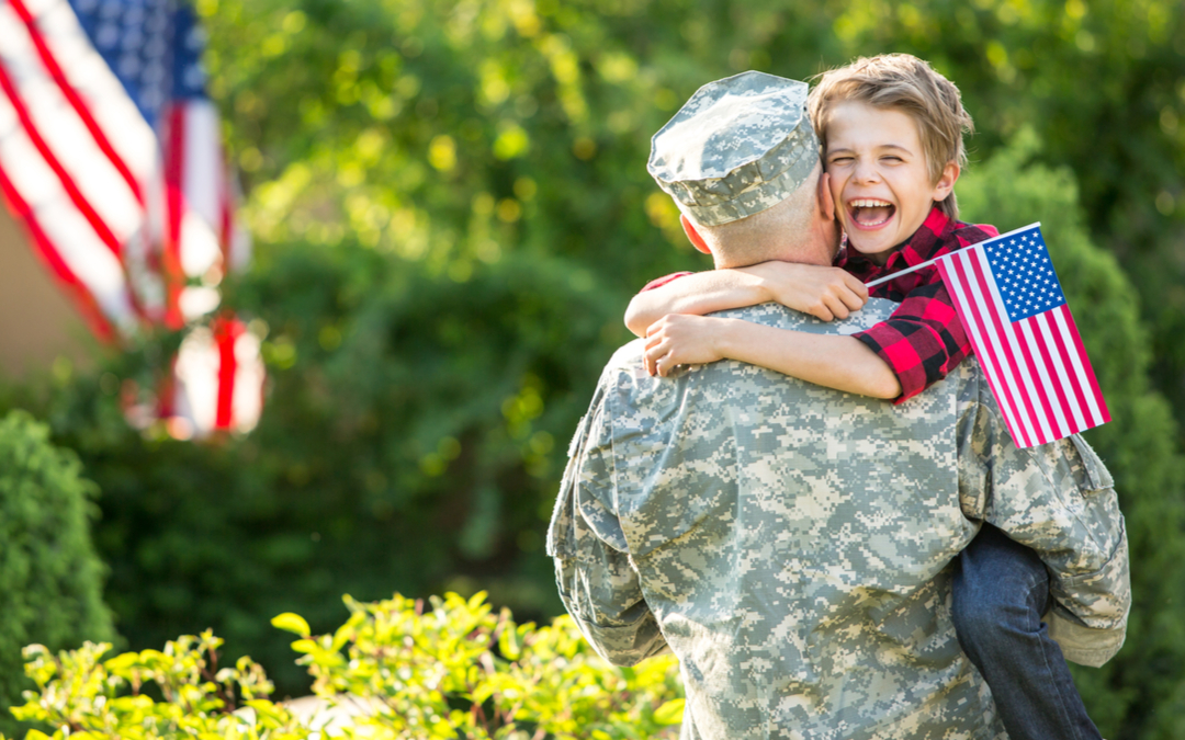 Member of the Armed Forces Hugging a Child Holding an American Flag