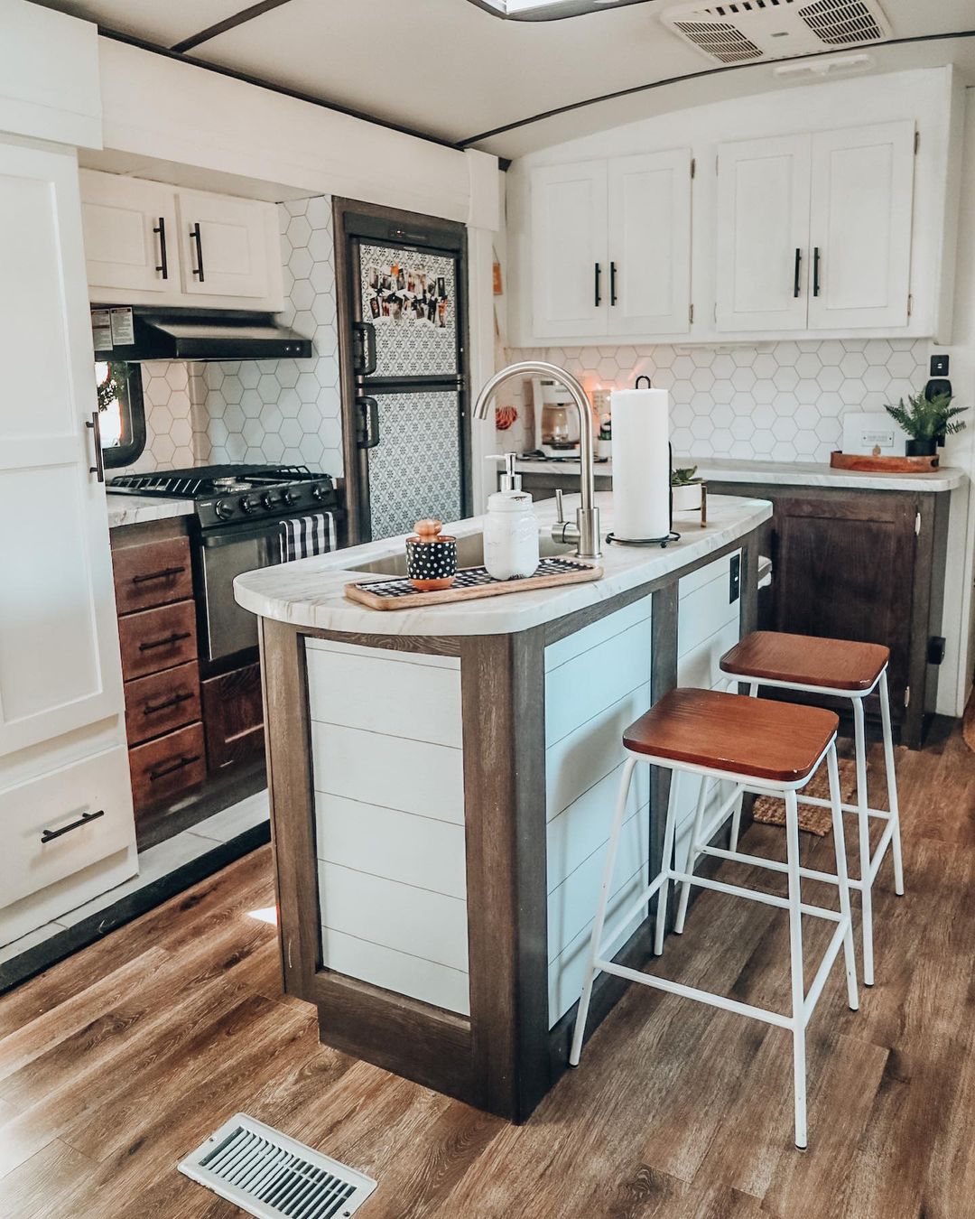RV kitchen showing bar stools behind the kitchen island as seating solutions. Photo by Instagram user @simplecatlady.