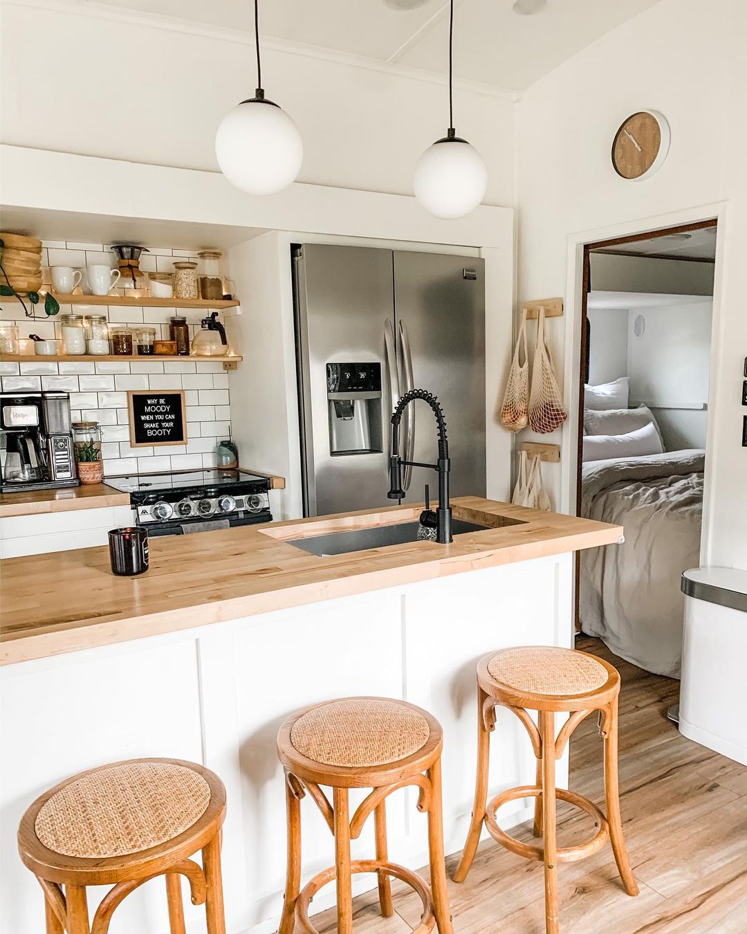 Breakfast bar also used as kitchen island, and a view of the full kitchen and master bedroom in an RV. Photo by Instagram user @laceyautumnbrooke.