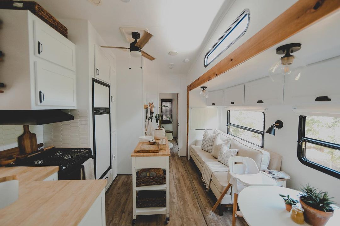 View of extended RV, including moveable island, kitchenette, kinette, and seating area. Photo by Instagram user @ourlivelytribervrenovations.