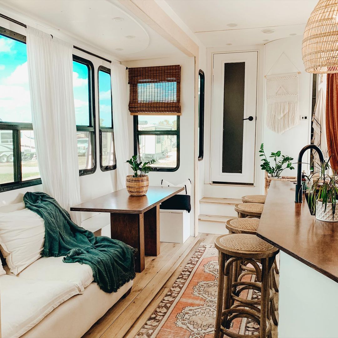 Seating area, including dinette and breakfast bar, with large windows in an RV. Photo by Instagram user @wholethompsonlife.