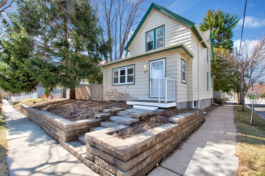Two story house with raised garden beds and yellow wood siding in St Paul. Photo by instagram user @korbyhometeam