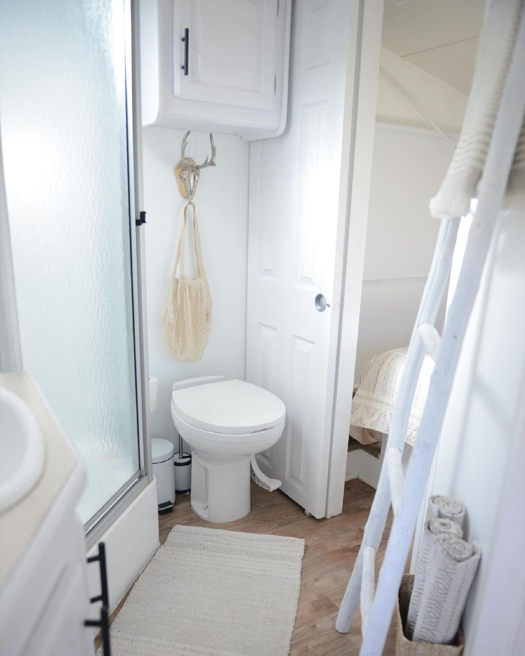 RV bathroom featuring toilet, cabinets, and stand-up shower. Photo by Instagram user @micasaesyuccasa.