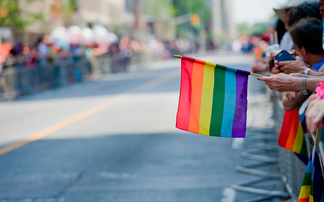 Rainbow Flag Being Held in Someones Hand at a Parade