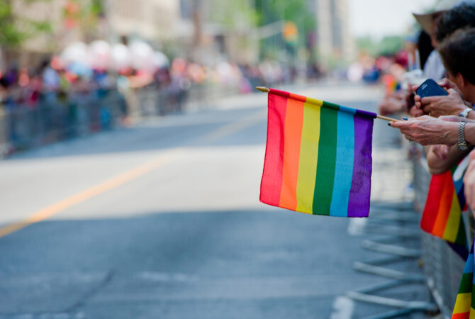 Rainbow Flag Being Held in Someones Hand at a Parade