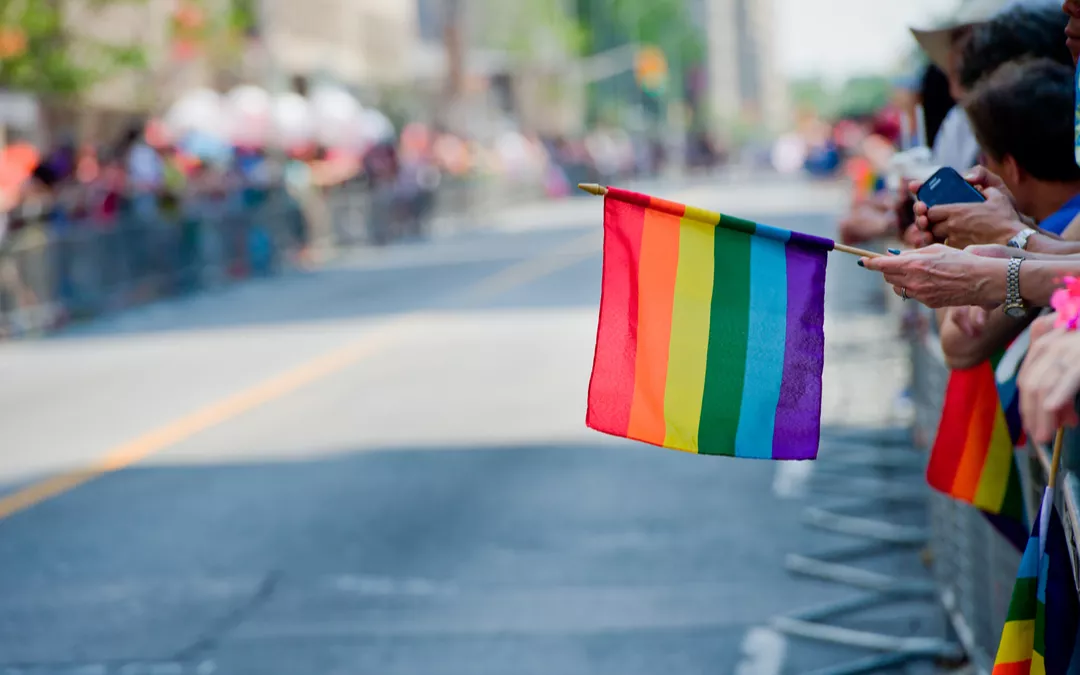 Rainbow Flag Being Held in Someones Hand at a Parade
