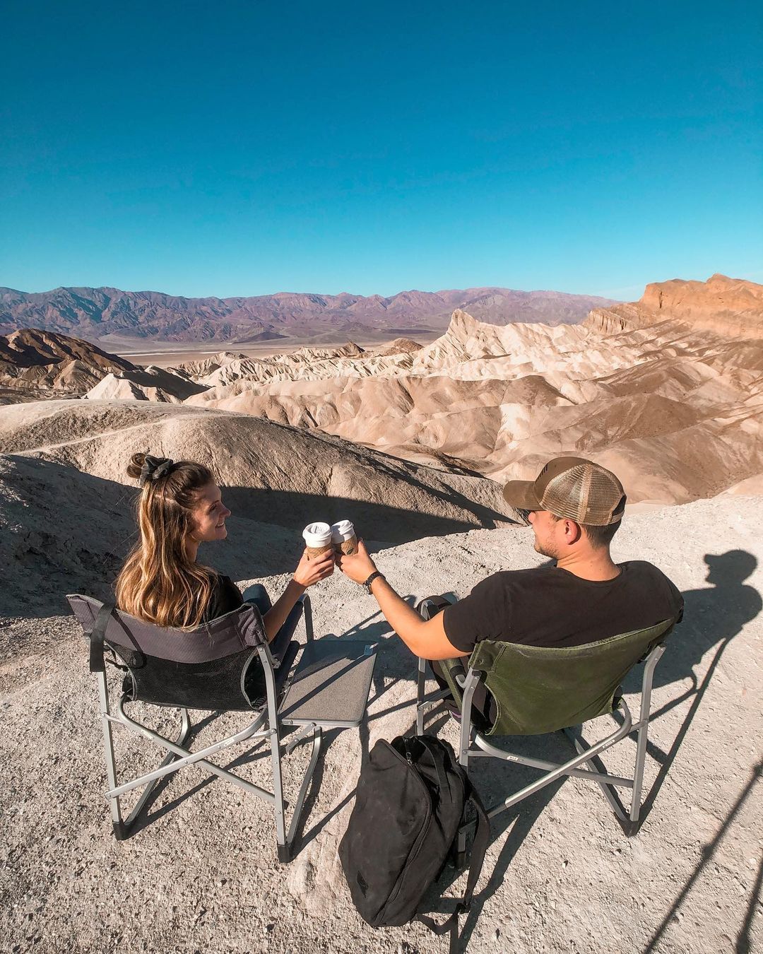 Two People Sitting on Camping Chairs in Death Valley. Photo by Instagram user @onworldtravel