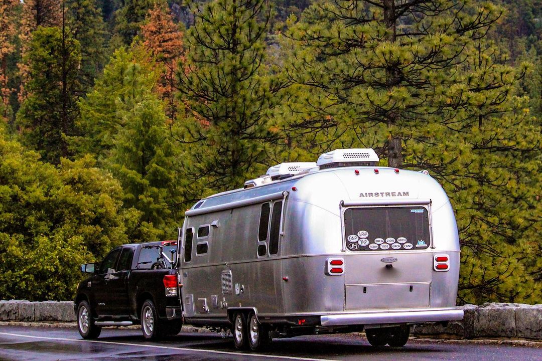 Airstream RV being pulled by a truck in scenic area. Photo by Instagram User @thisairstreamlife