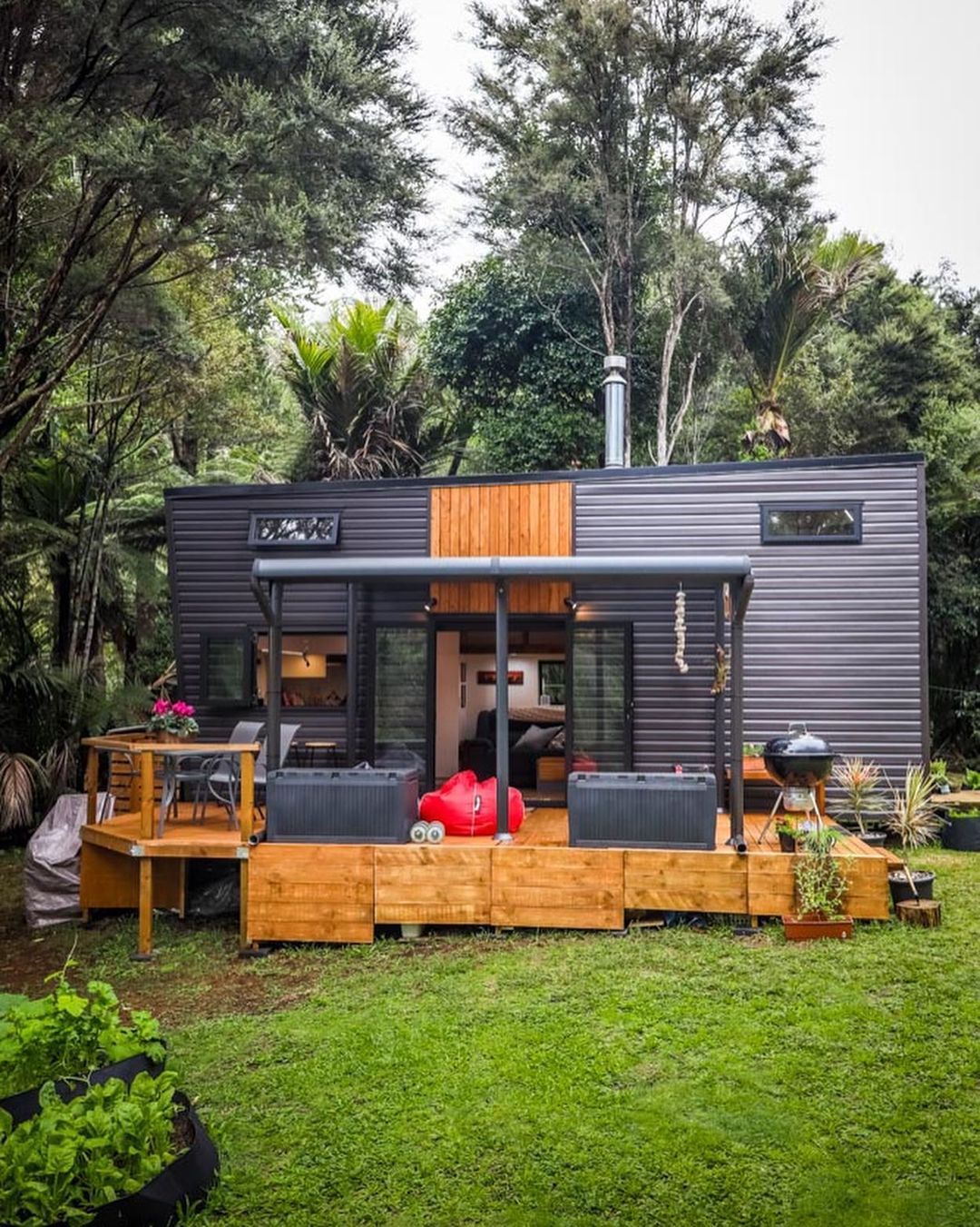 Modern shipping container home with wood accents and a large front porch. Photo by instagram user @livingbiginatinyhouse