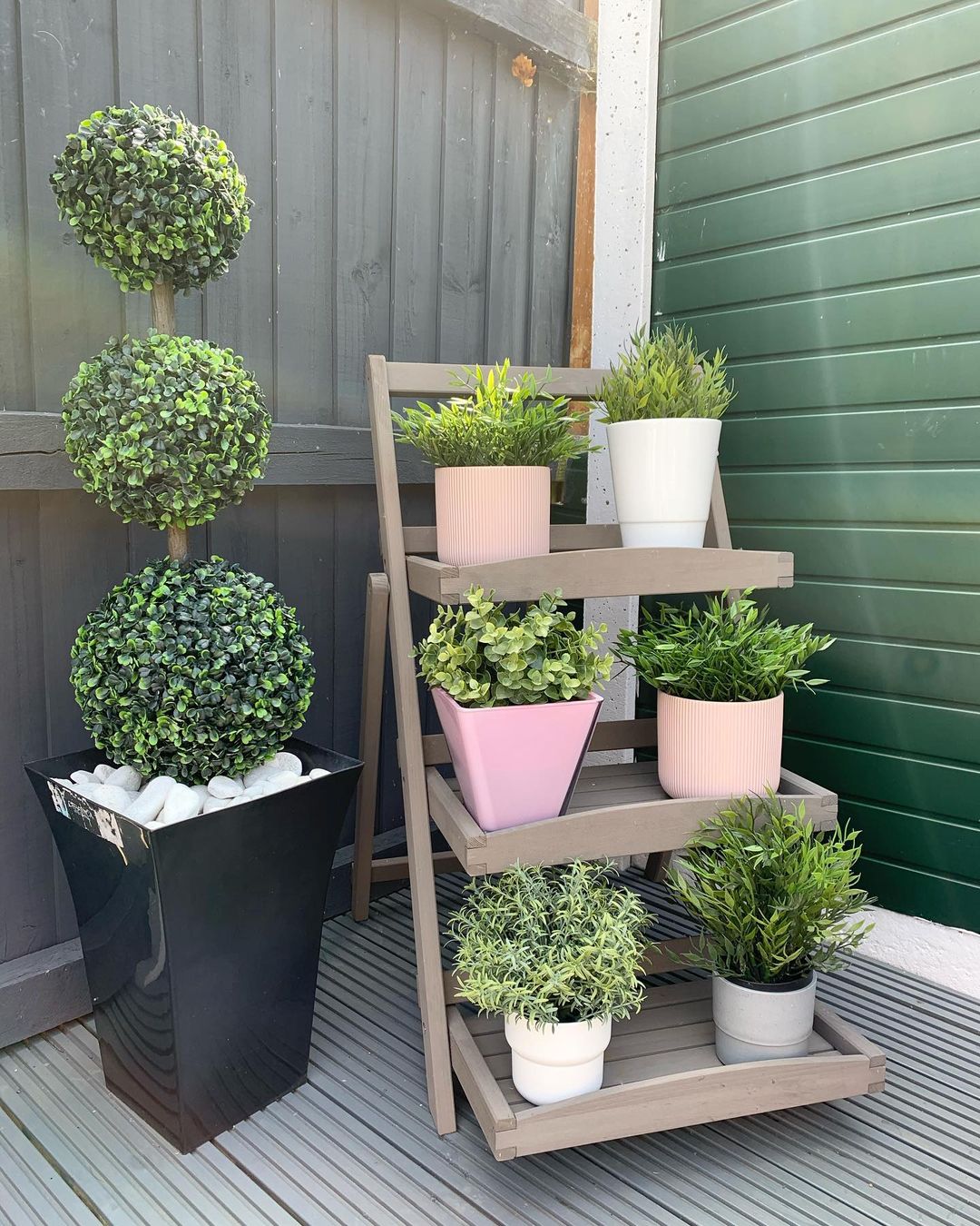 Garden ladder with potted plants painted different colors in a quiet corner. Photo by instagram user @millsfieldfamilyhome