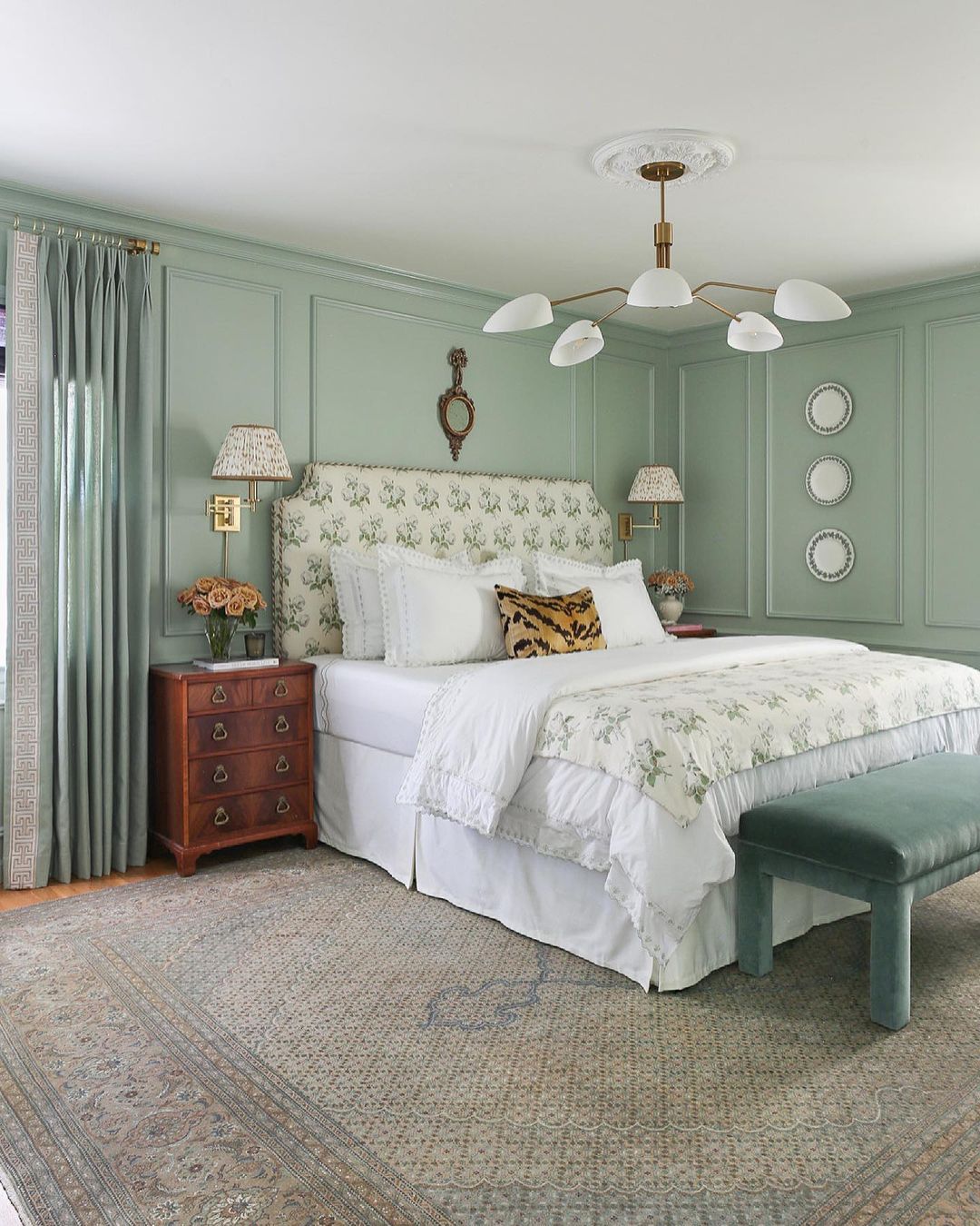 Painted green bedroom with a fluffy white duvet cover and green ottoman with sage walls and curtains. Photo by instagram user @aglassofbovino