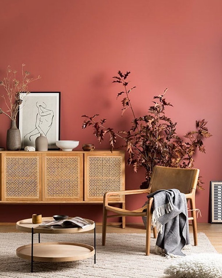 Sitting area with wooden fixtures in front of a red wall and a red accent plant. Photo by instagram user @the_good_painter