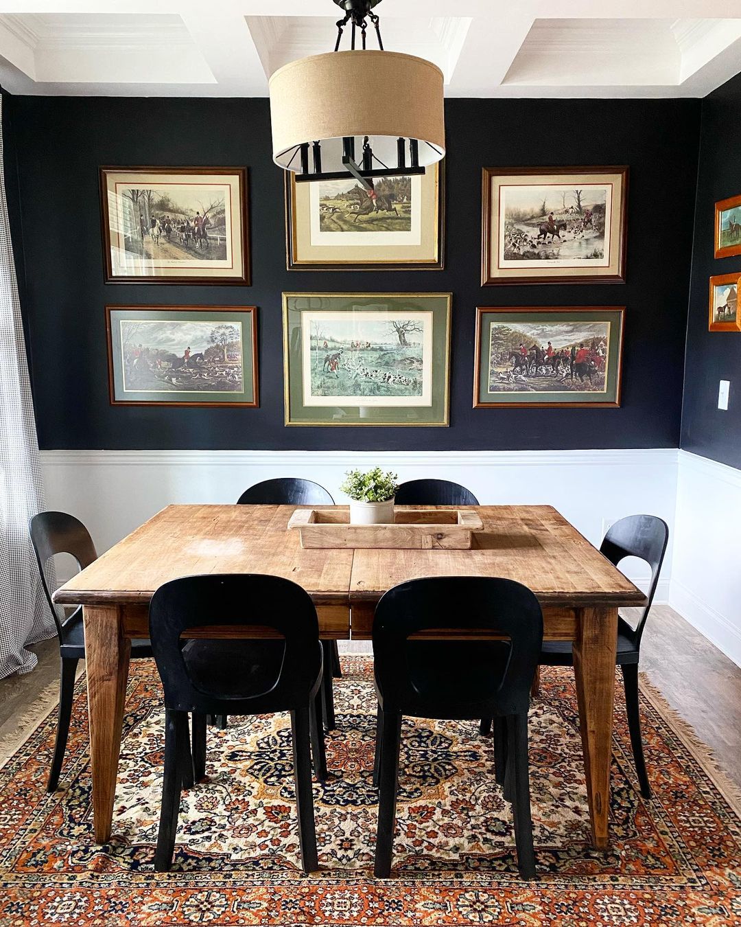 Dining room with black and white walls with black chairs around a square table and a gallery wall. Photo by instagram user @emilykayrichardson