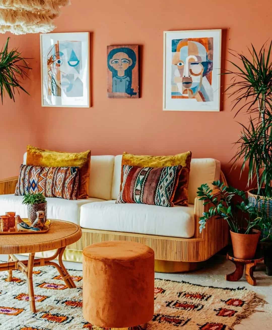 Orange room with a couch and orange artwork with a terracotta planter and ornate rug. Photo by instagram user @relevanceinternational