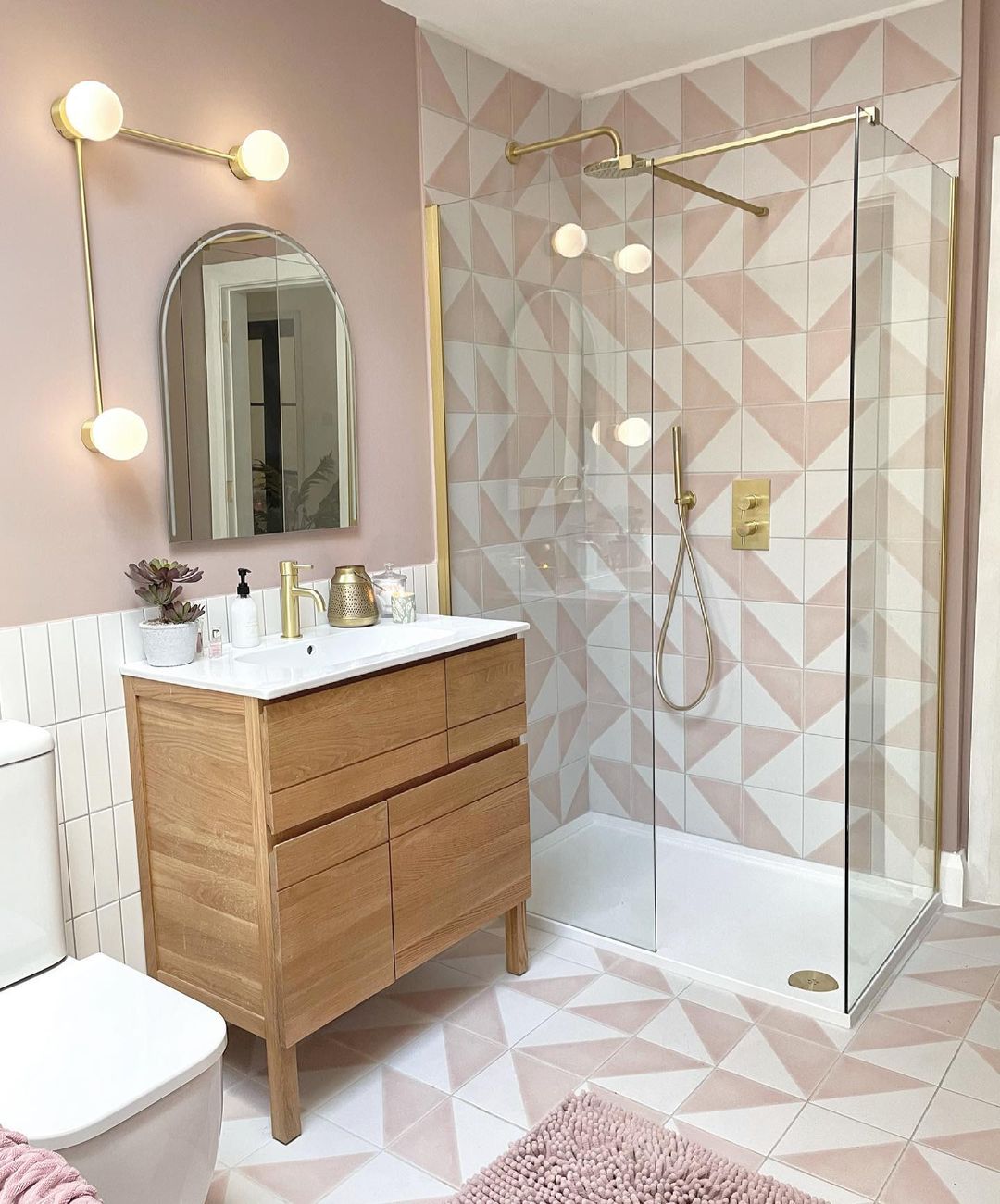 Modern bathroom with pink accented tile and new light fixtures. Photo by instagram user @ournestintheglen