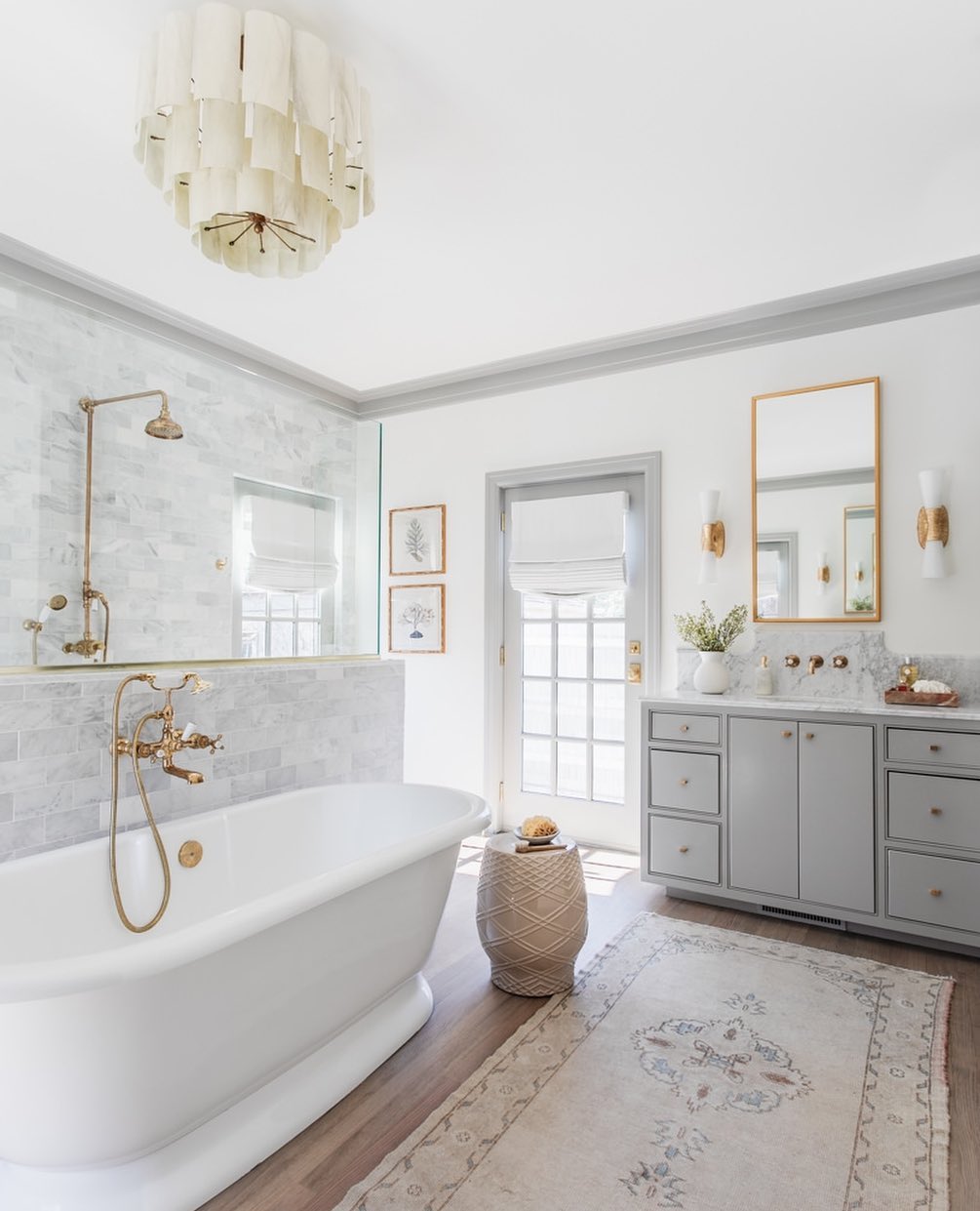 Gray bathroom with a free standing tub and nice rug with a chandelier. Photo by instagram user @emilyhartphoto