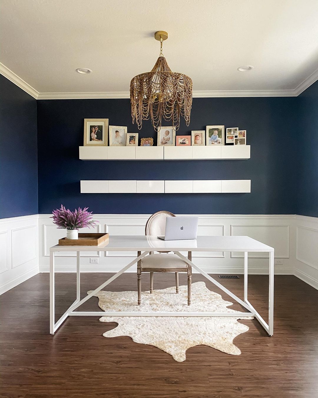 Simplistic office with blue and white walls and a shelf of pictures. Photo by instagram user @firsthouseonfinn