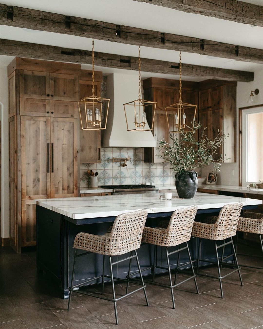 Feng Shui wood element interior design featuring a modern kitchen with a large island and brown cabinets. Photo by instagram user @graceddesigns