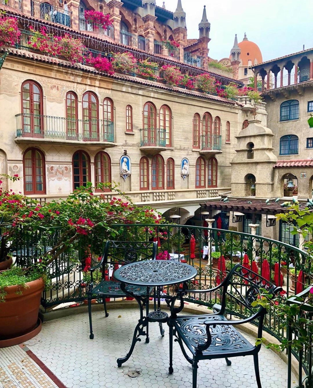 Perspective of wrought-iron bistro set on a balcony overlooking the Spanish Patio. Photo by Instagram user @missioninnhotel.