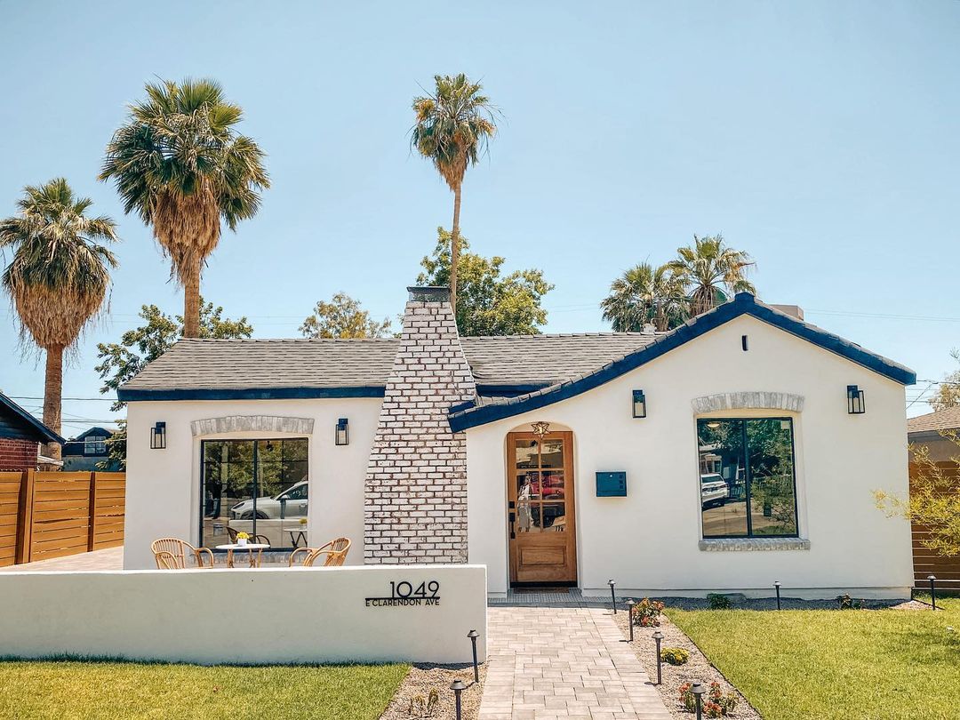 Spanish style home in the Encanto neighborhood of phoenix with a white exterior, stone chimney, and navy trim. Photo by instagram user @desertstyleaz