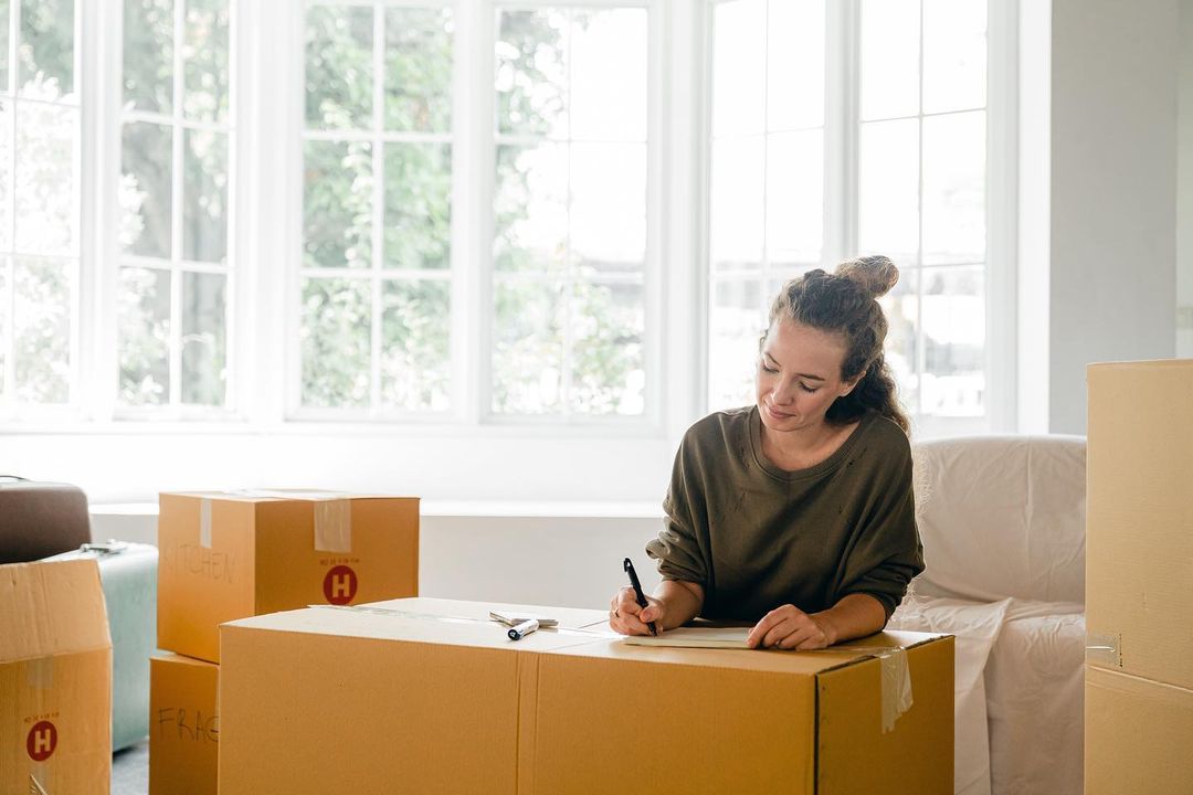 Woman Writing On a Moving Box. Photo by Instagram user @apacrelocation