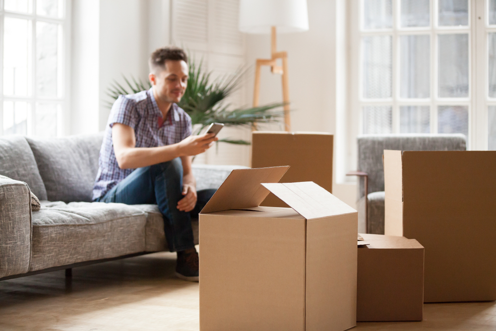Man Sitting on the Couch Among Moving Boxes