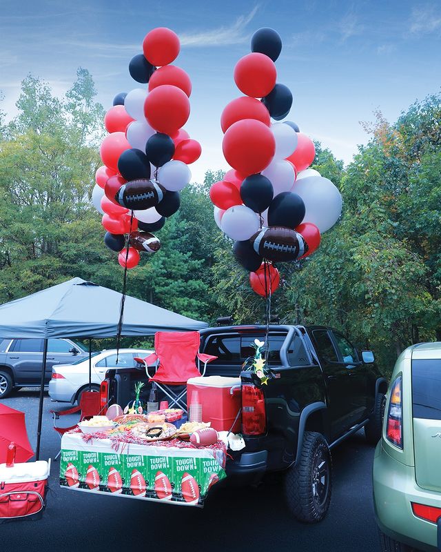 Black pickup truck with a tailgating party on its tailgate with red, white, and black balloons. Photo by instagram user @safelite