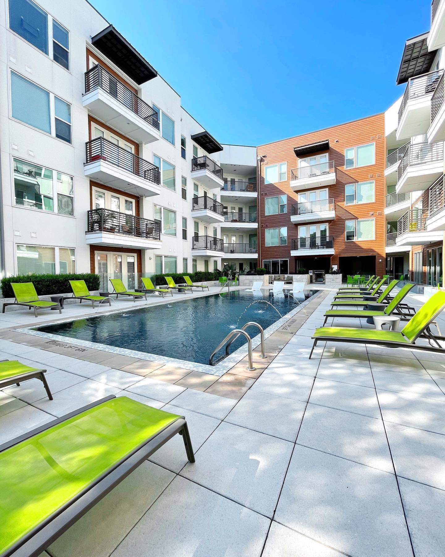 Modern apartment complex with large swimming pool and lounge chairs located in South Lamar neighborhood in Austin, TX. Photo by Instagram user @grovessouthlamar.