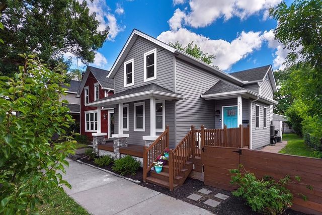 Gray house in Cleveland with a small brown deck, modern fence, and a bright blue door. Photo by instagram user @headbeck