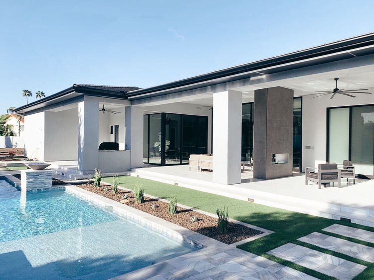 Backyard of a modern home with a rectangular pool and a courtyard the connects rooms together. Photo by instagram user @phxhomebuilde