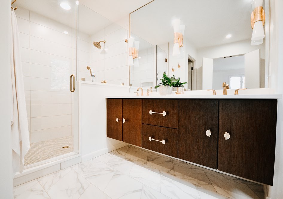 Bright modern home bathroom with a large window, dark wooden cabinets, and bright lighting. Photo by instagram user @mccamyconstruction